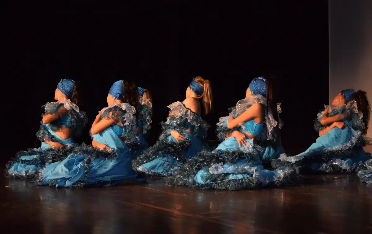 Troupe dancers performing synchronized group choreography on a ballroom dance floor