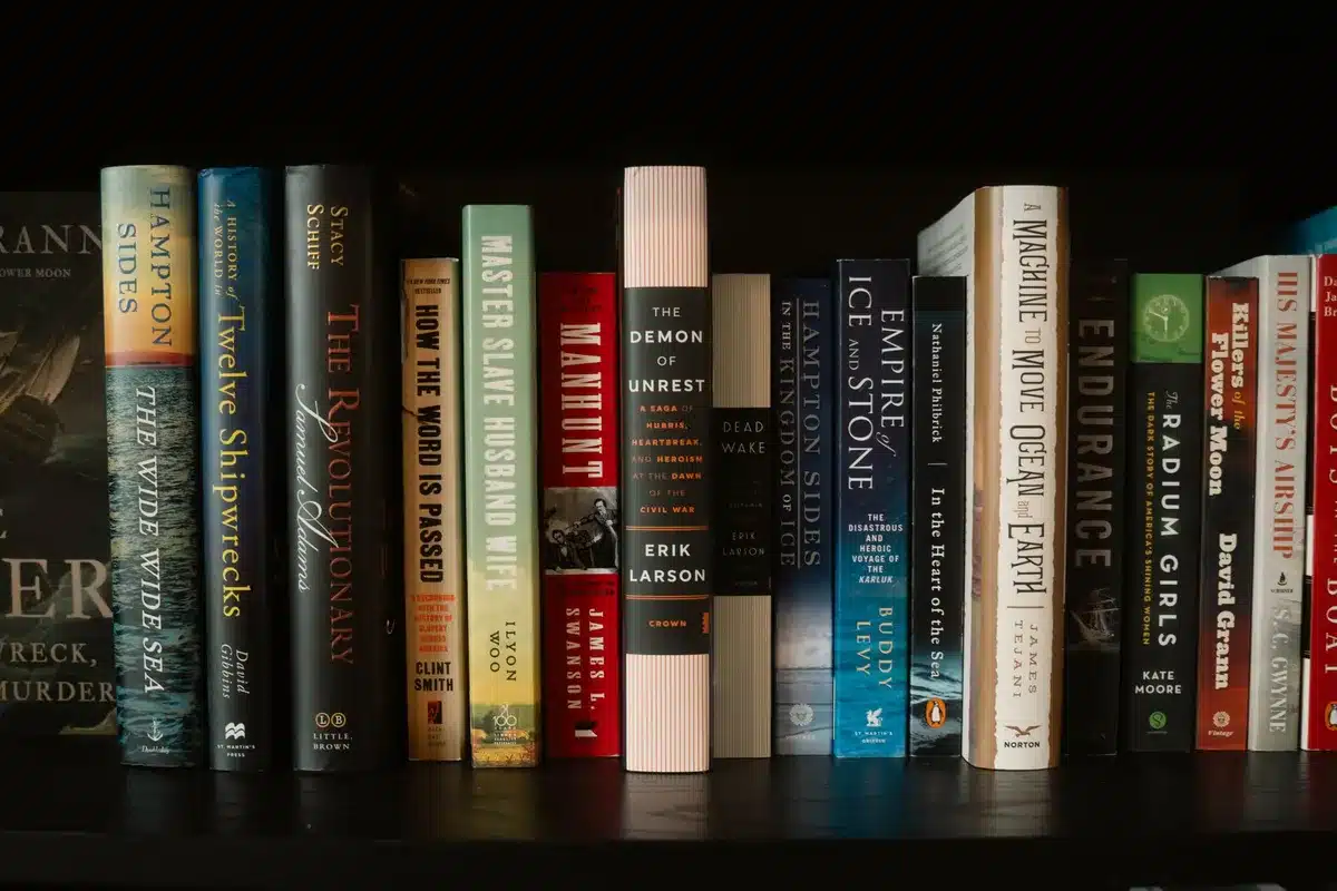 Oversized comic book editions stacked on a shelf with a hand reaching toward them