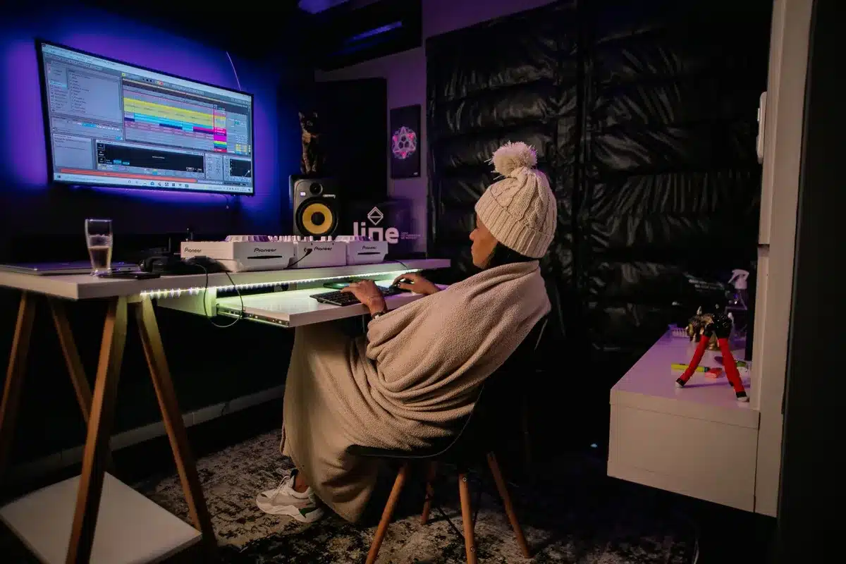 Music producer working at a mixing console in a modern studio with glowing screens and neon lighting
