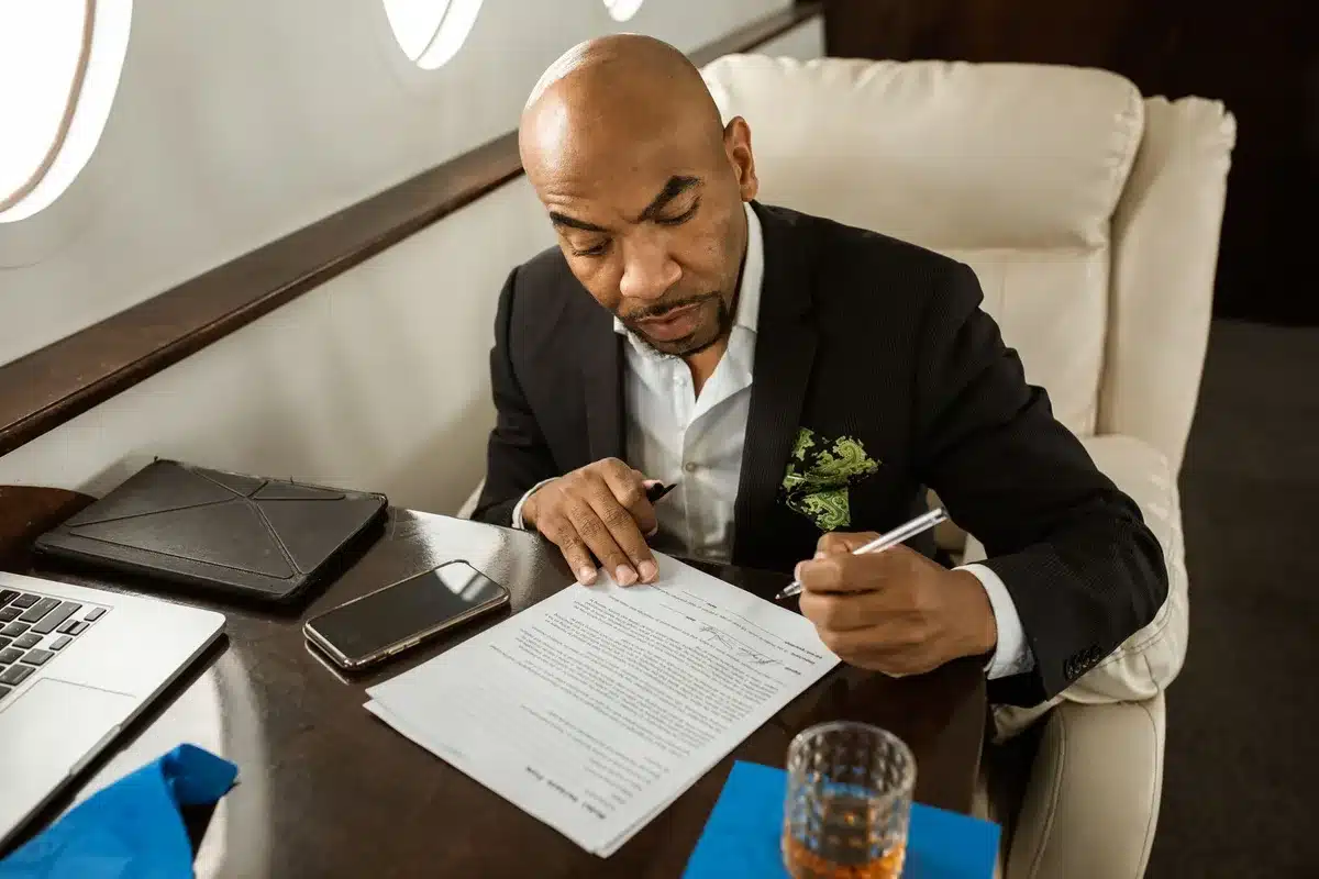 Film executive reviewing acquisition documents and contracts at a desk in an office setting