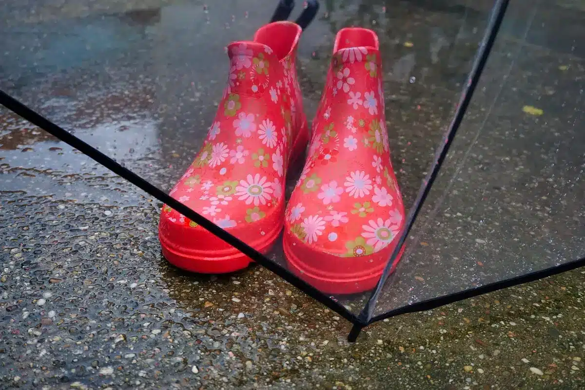A pair of anonymous feet stepping into cozy boots on a cobbled street with fallen leaves scattered around, no visible brand