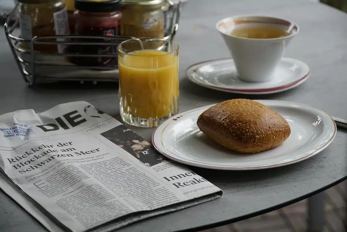 A vintage newspaper folded open to the comics section, with colorful comic strips visible, a coffee cup beside it, morning light creating soft shadows across the page.
