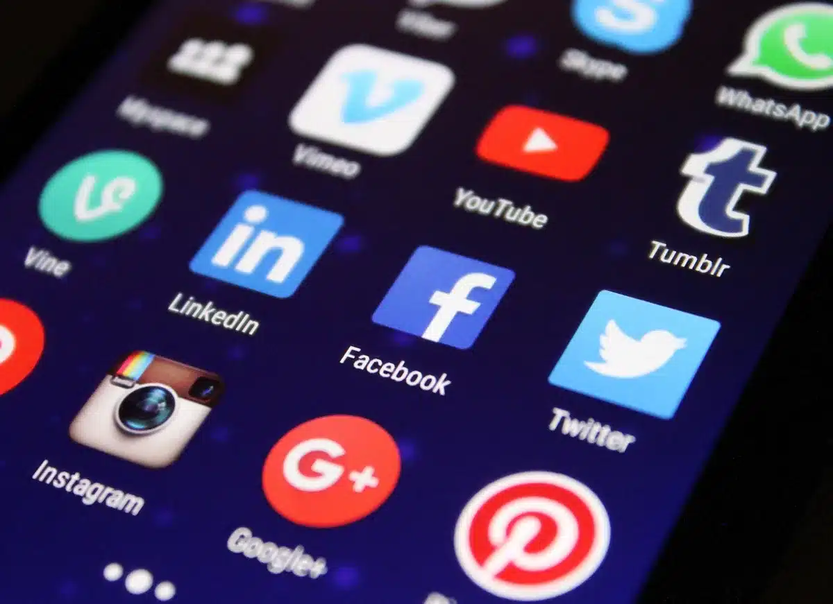 Hands holding a phone showing social media posts of tributes