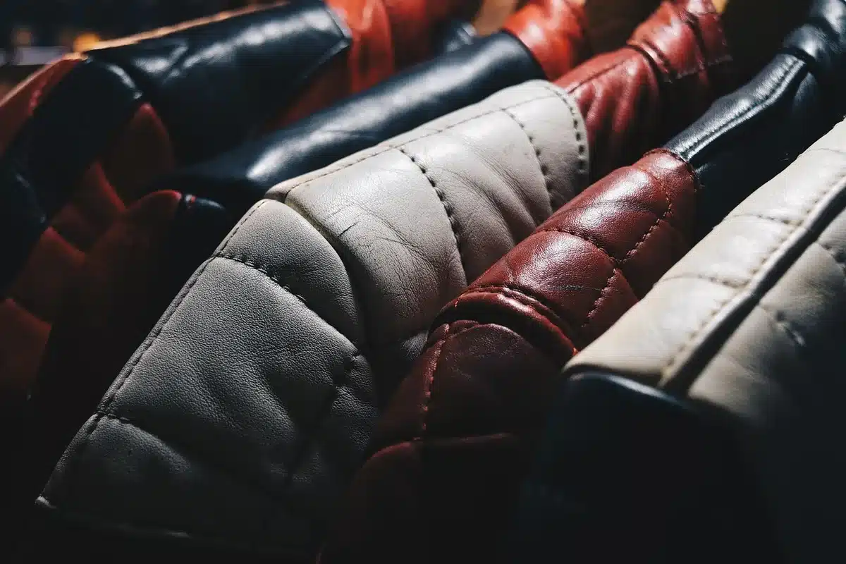 A collection of fall jackets in various textures and colors arranged on a neutral surface, showing suede, plaid, and solid options