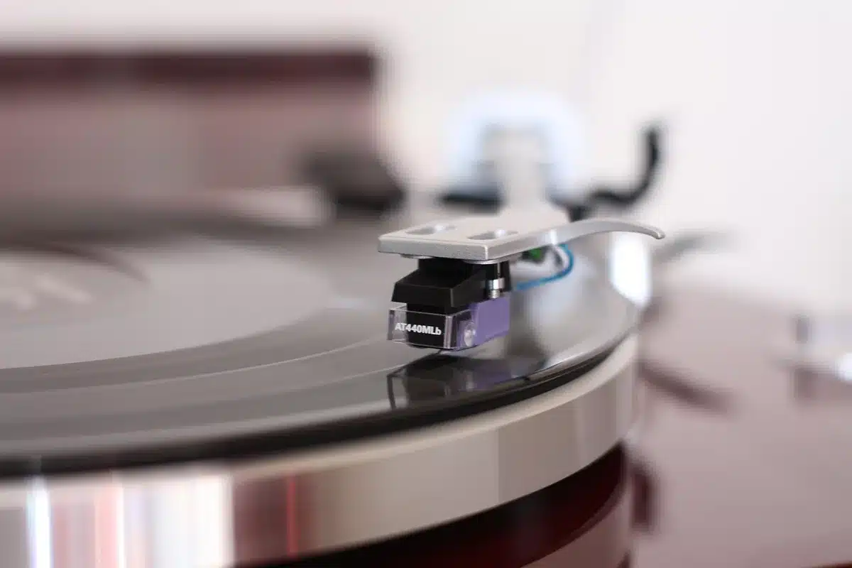 Close-up of a record player and a tracklist under soft light, suggesting album sequencing