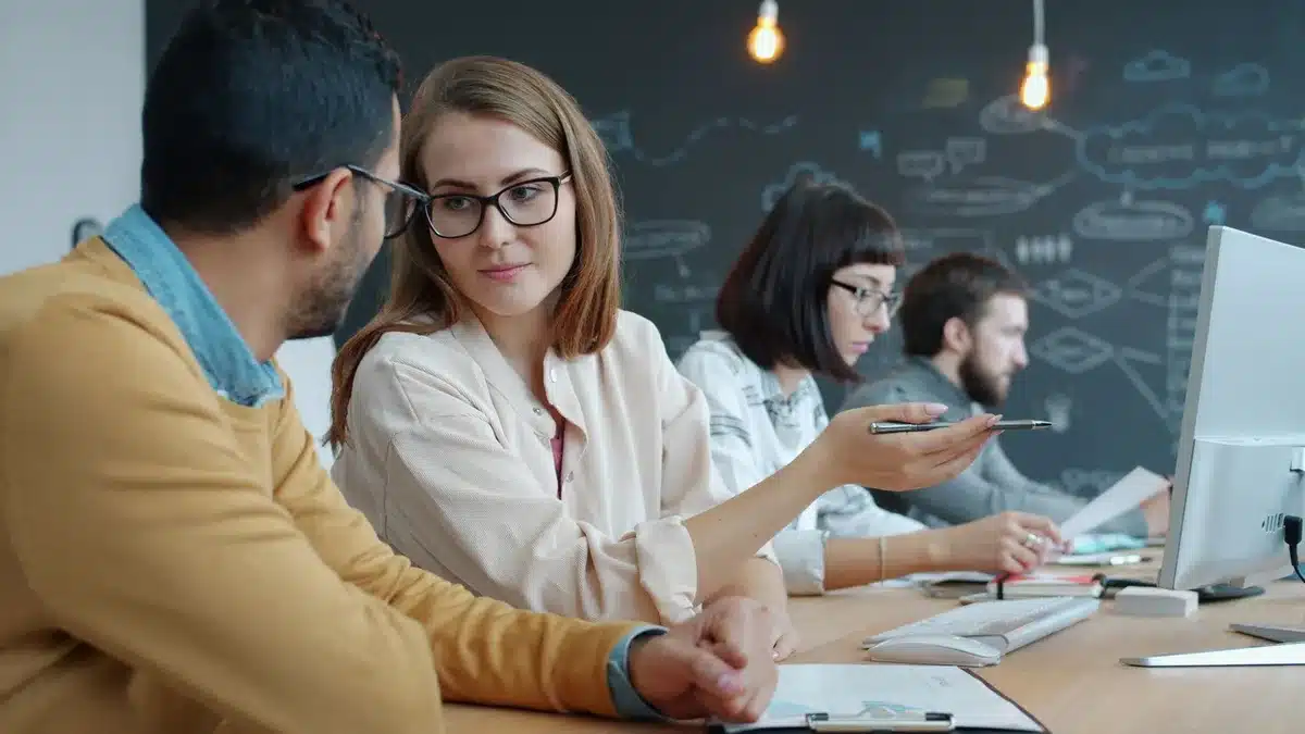 Two young colleagues exchanging tense conversation in an office
