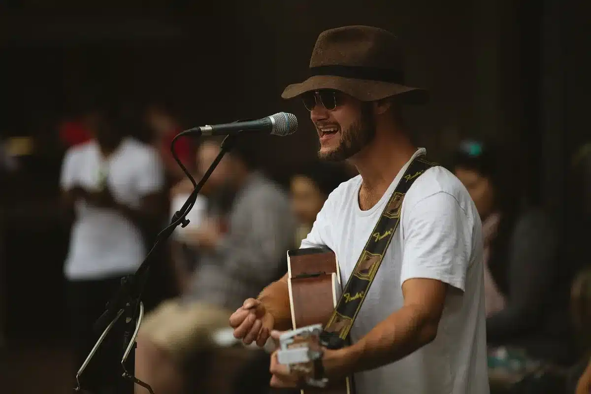 An anonymous small crowd gathered outside a low-key music venue, figures blurred and holding up phones with screens glowing, a warm communal mood of support and relief