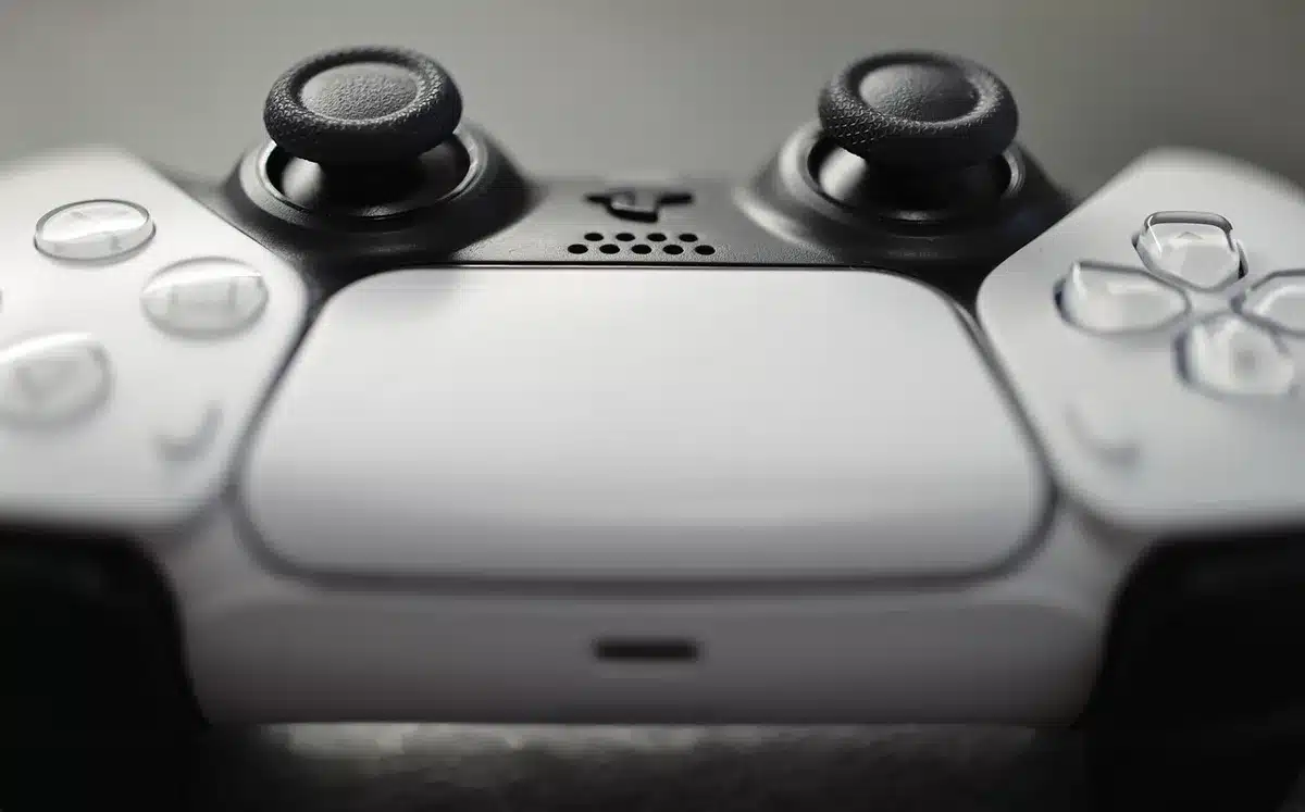 PlayStation controller on a desk beside a screen showing gameplay footage