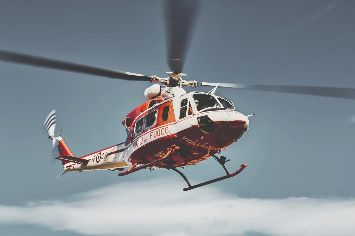 Emergency responders at helicopter crash scene with wreckage and debris