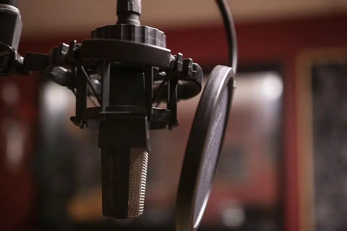 An empty vintage microphone beside a small toy robot and a script on a dim studio desk