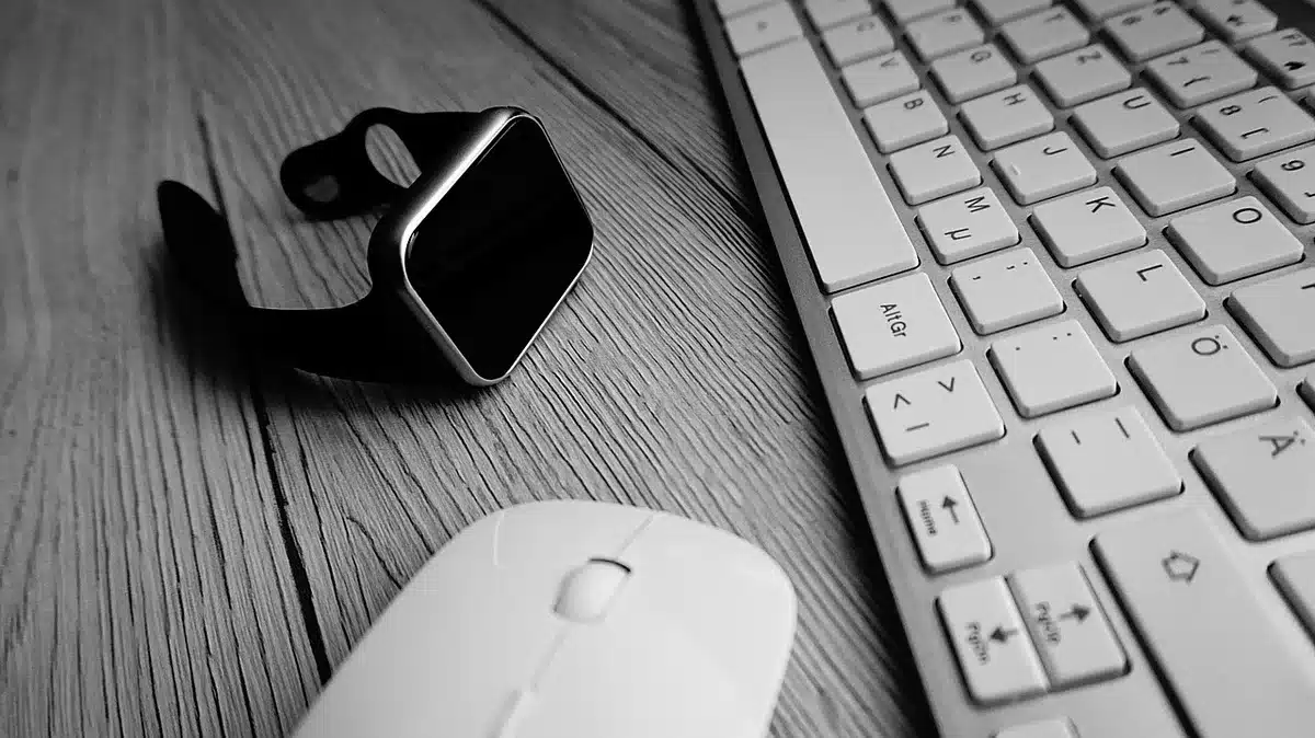 A close-up scene of an unbranded smartwatch resting on a neutral tabletop next to an anonymous charging puck and a folded soft cloth, soft studio lighting, no logos visible