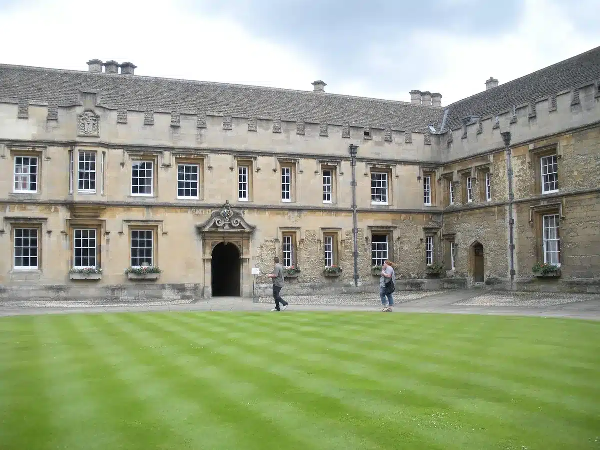 Students walking on a manicured boarding school campus lawn, faces not identifiable