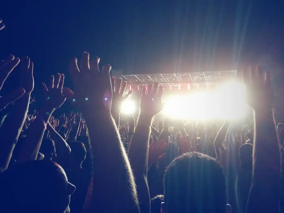 anonymous crowd of fans silhouetted under arena lights, hands raised and confetti falling