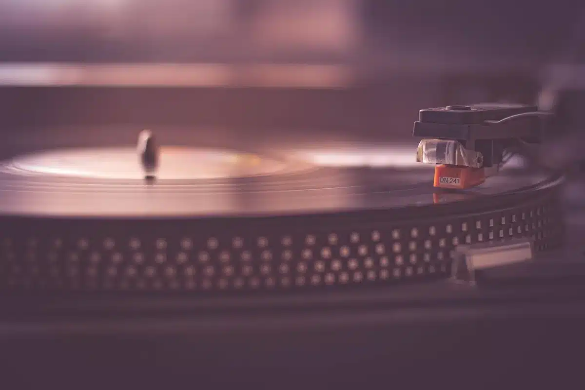 Vinyl record on turntable in a dimly lit studio with microphone and notes nearby