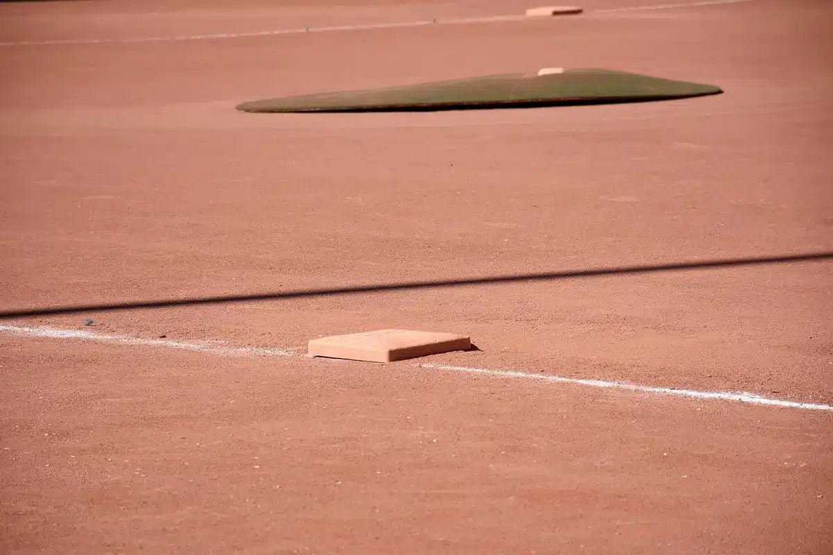 Baseball player sliding into base during a play, showing signs of physical strain