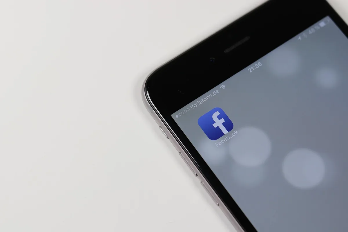 Close-up of a hand holding a smartphone showing a social media post in a dim backstage setting