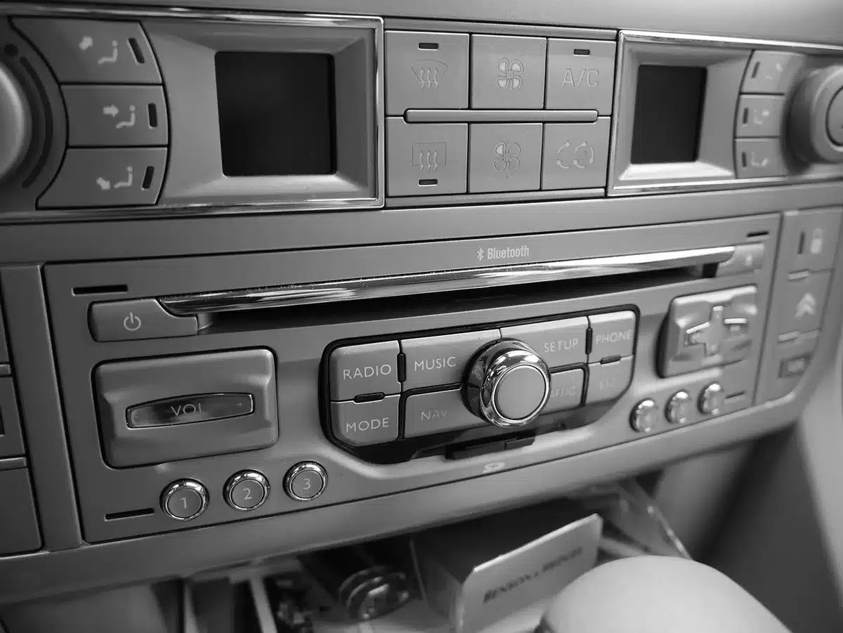 Close-up of a radio console with faders and a blinking on-air sign, no people visible, paper notes taped near knobs — evokes broadcast work behind winners