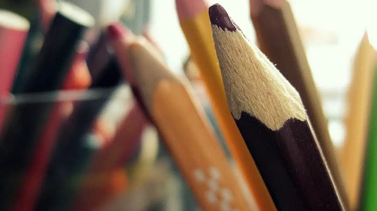 Artists sketching at a convention table, hands and pens visible, anonymous crowd