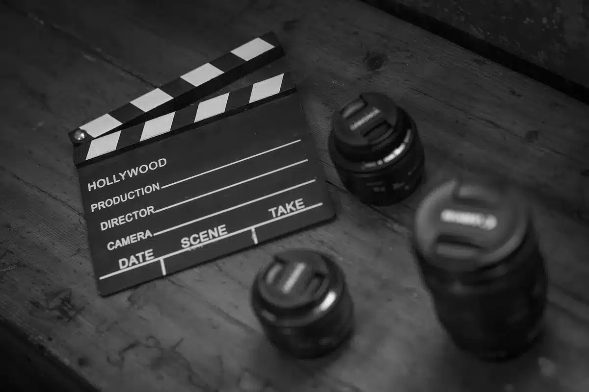 A close-up of a blank clapperboard on a table beside a stack of unmarked scripts, the slate slightly ajar and ready for a take, suggesting projects concluding