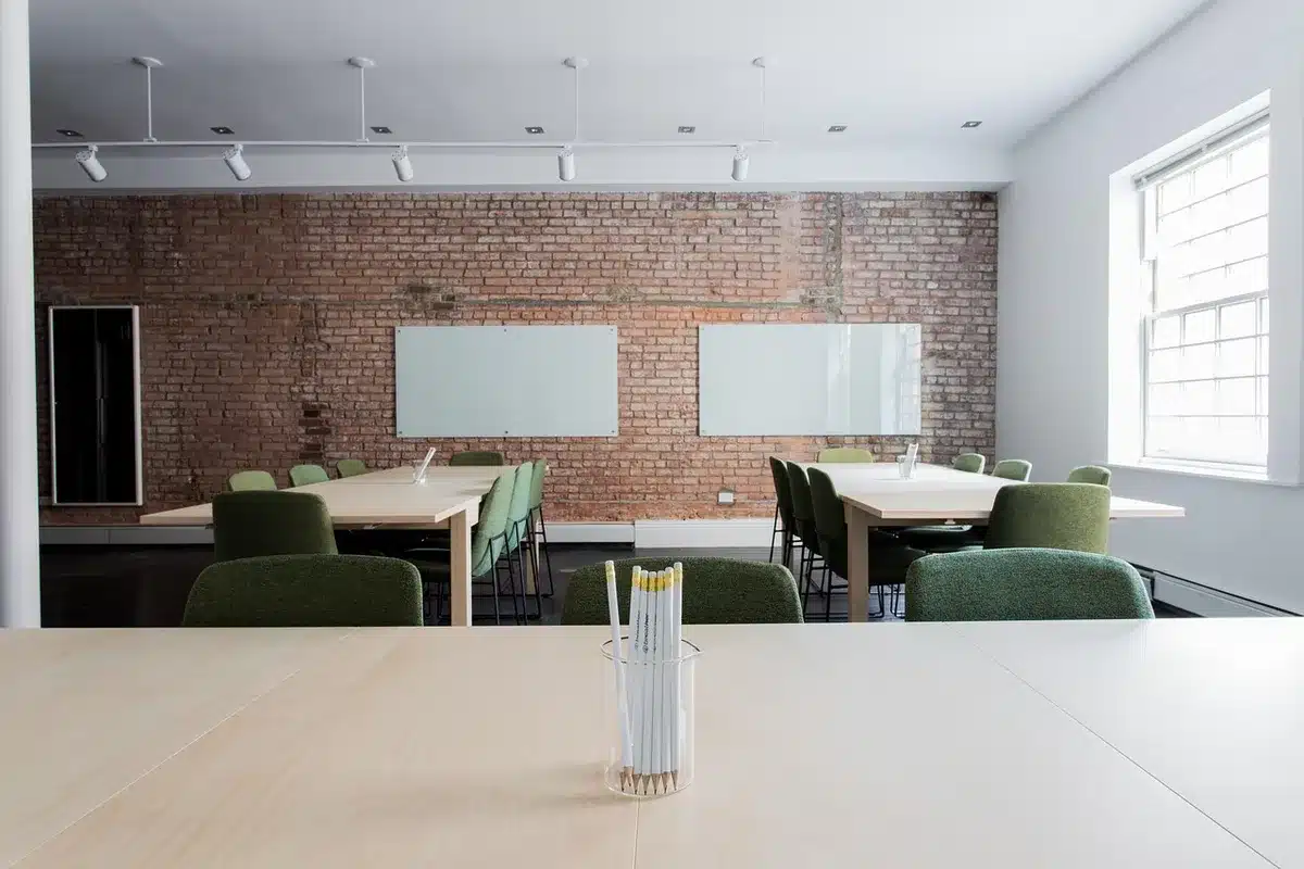 Empty boardroom table with scattered documents and laptops