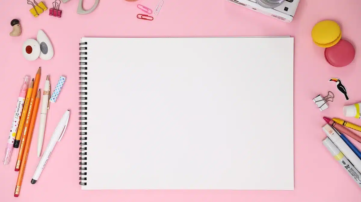 A close-up of an open sketchbook page showing a single-panel black-and-white cartoon drawn in ink, a penciled caption beneath, no identifiable faces or logos