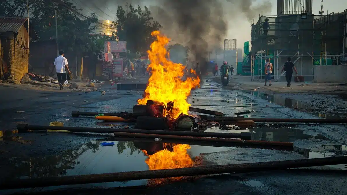 Silhouetted costumed figure amid rubble and smoke on a city street at dusk