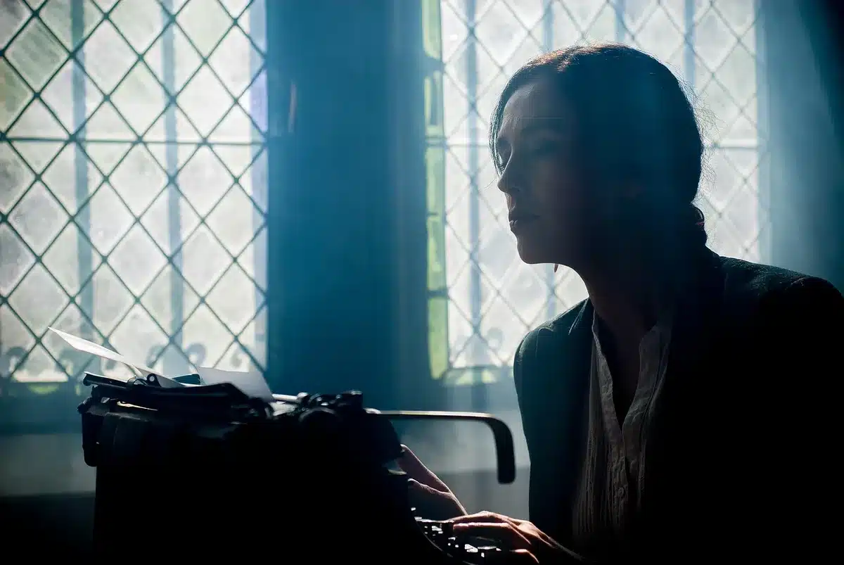 Typewriter and feminist magazines on a desk with a lit candle, symbolizing legacy