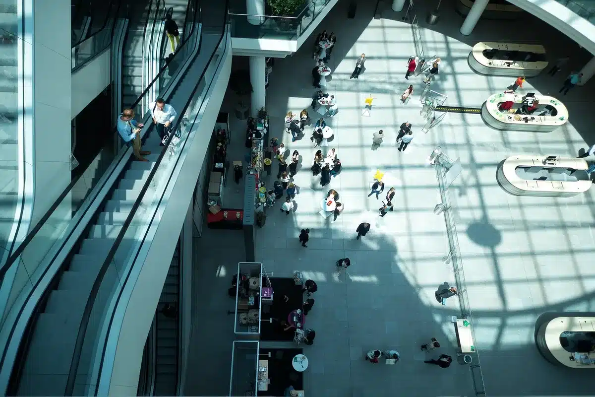 A deserted comic-book convention corridor with scattered promo posters hinting at a monstrous green silhouette on the walls, empty badge tables and a lone folded program on the floor