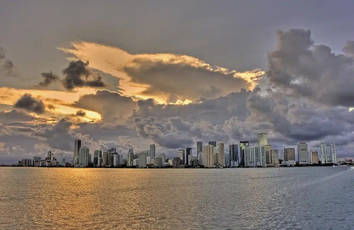 Miami skyline with high-rises and marina at golden hour, anonymous suited silhouette