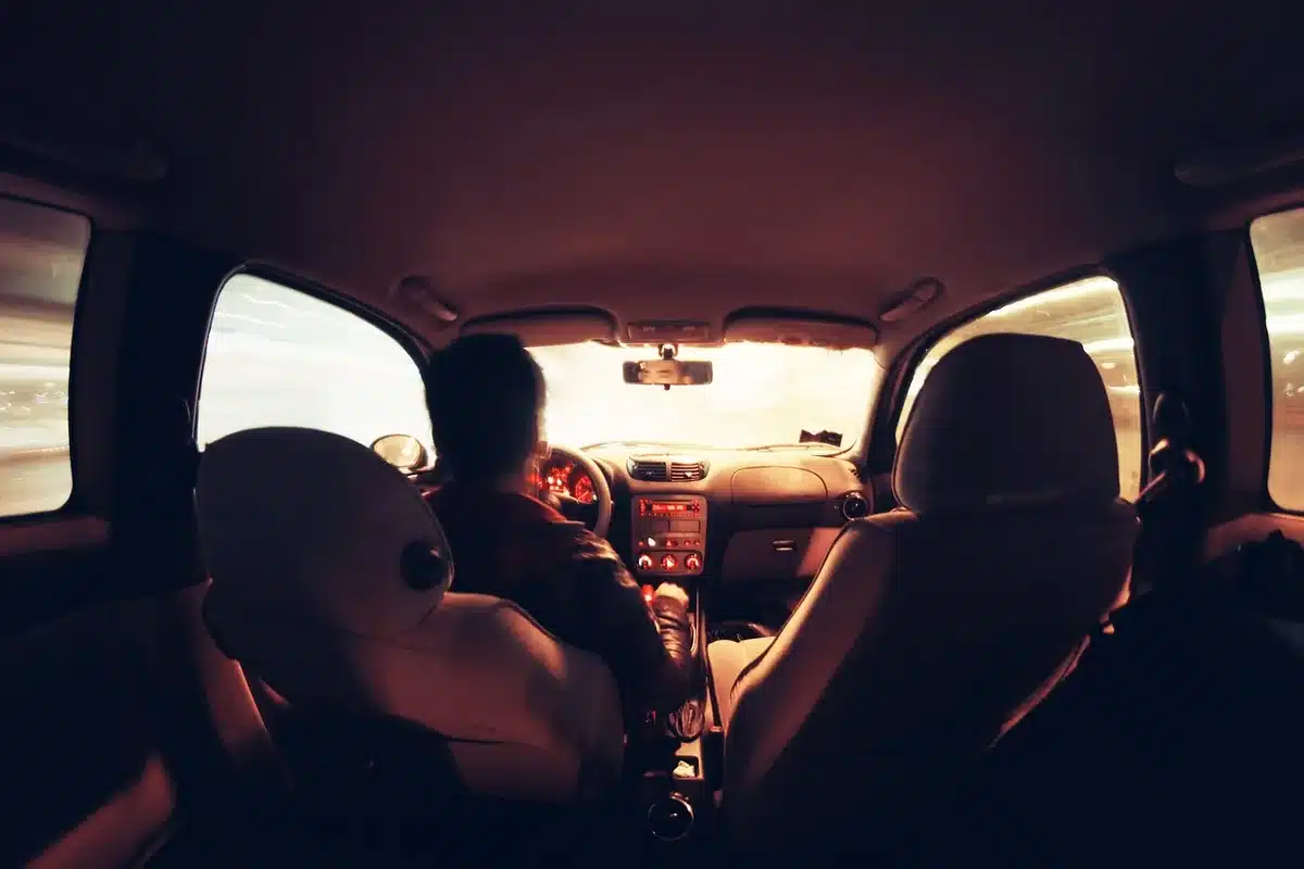 Camera on a dashboard and a yearbook on a passenger seat with a sunlit desert highway outside