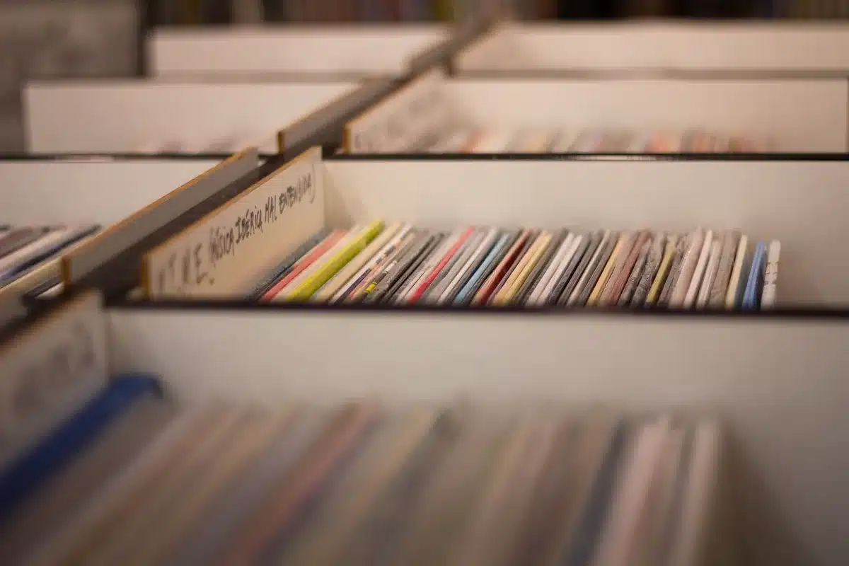 Stack of unbranded vinyl records leaning against a record sleeve, a handwritten composer note on top and a pen nearby, evoking a publisher's catalog