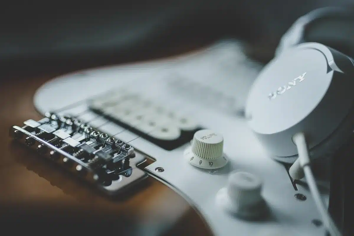 An empty neon-lit honky-tonk barroom with a lone acoustic guitar on a stool, a folded setlist on the stage and a sunbeam through dusty windows