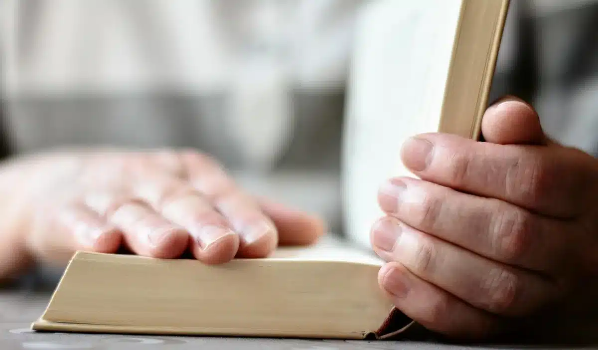 A split bar counter with an open Bible on one side and a stack of guitar picks and a capo on the other, soft morning light across the wood