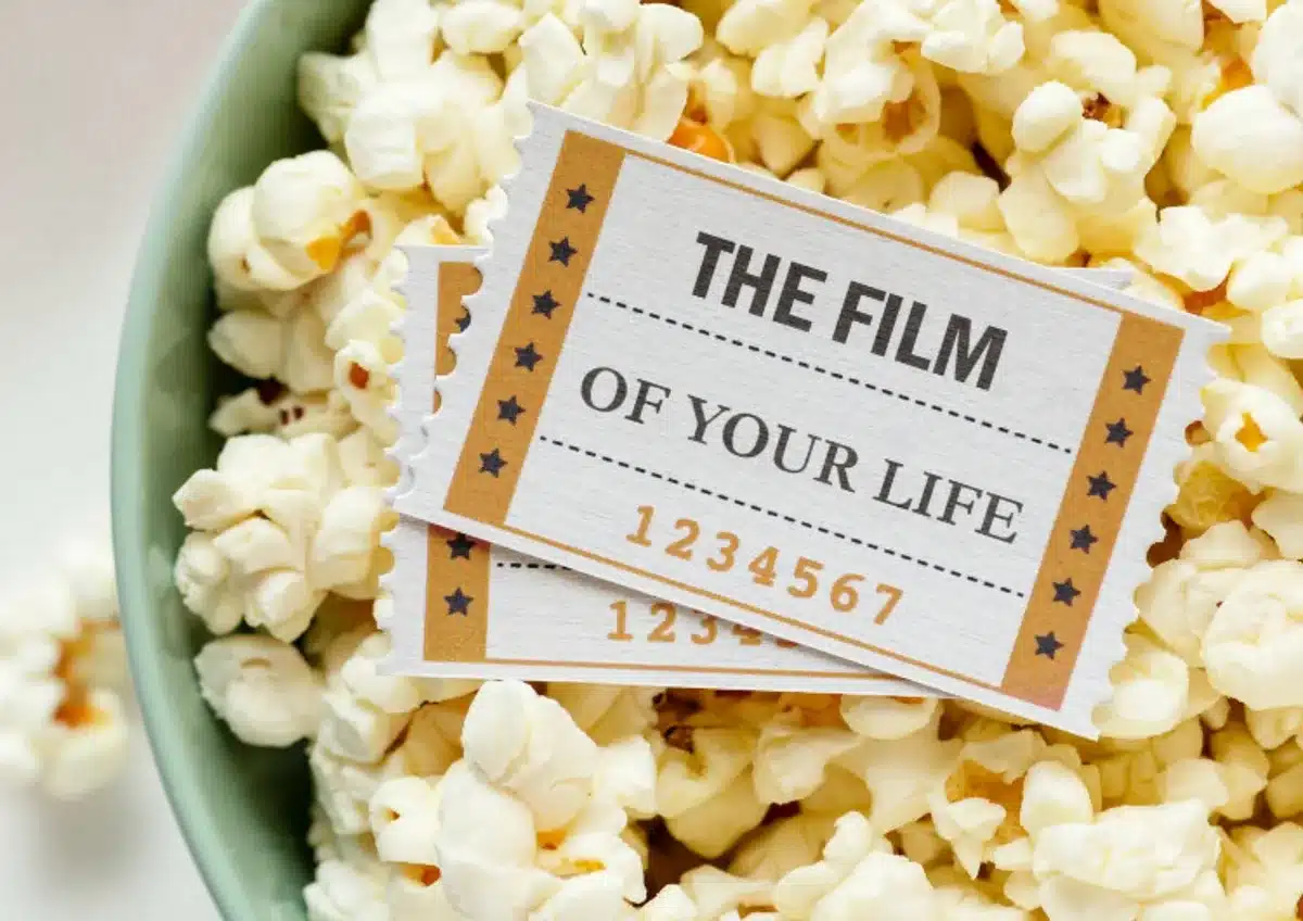 Anonymous crowd in a theater lobby holding popcorn and tickets, queuing to enter