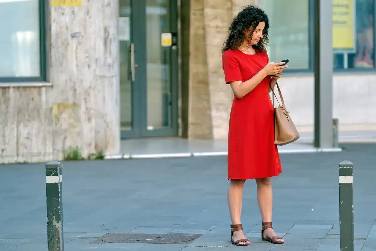 A compact playlist on a smartphone screen held over a coffee table, no hands identifiable, earbuds and a blank notebook beside it