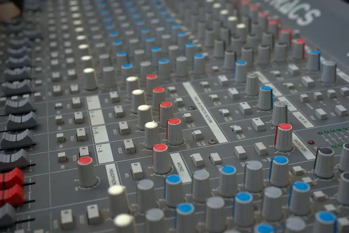 An empty recording studio control room with a vintage mixing console, scattered notes and a pair of unbranded studio headphones on the desk, late-afternoon light through a single window