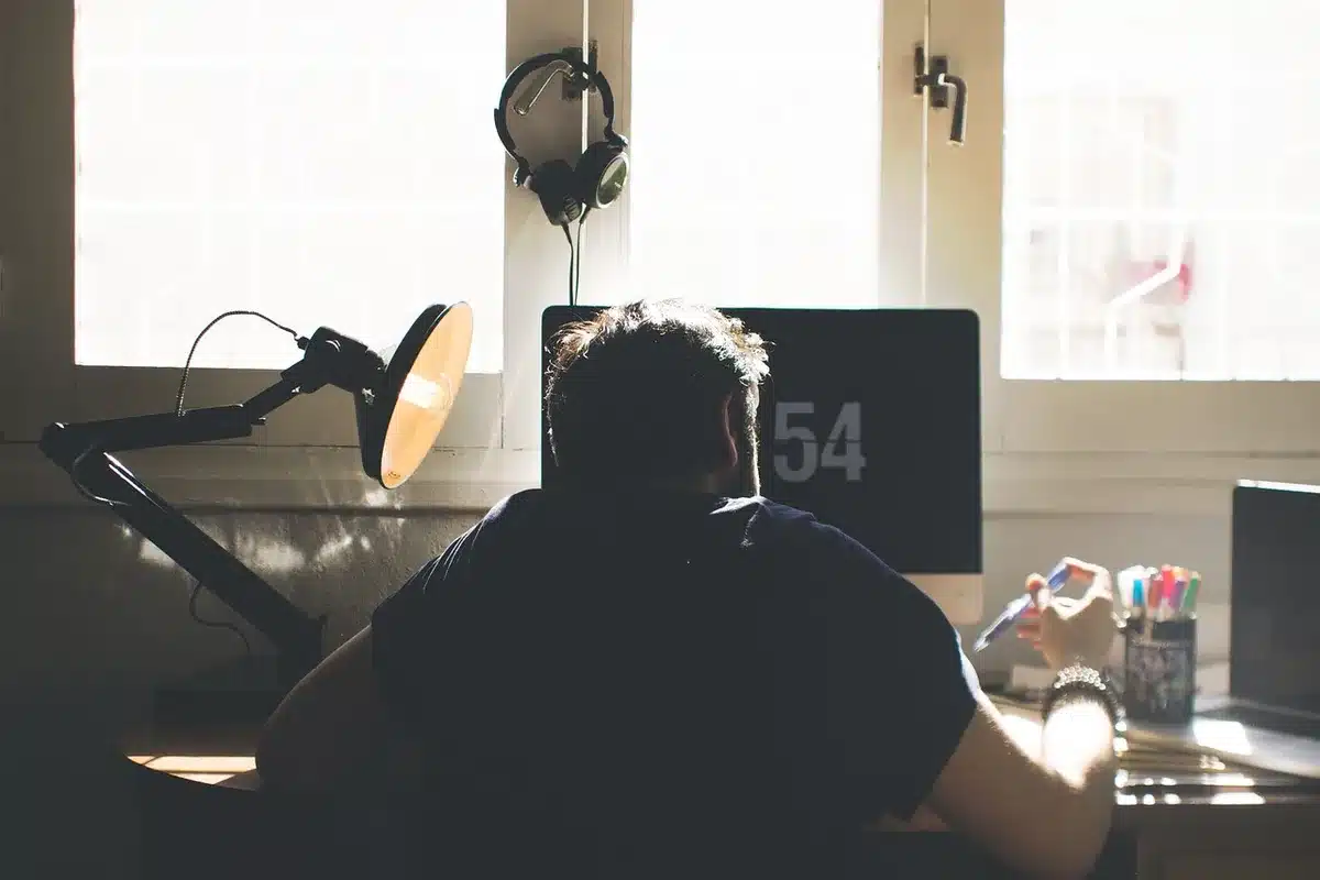 Person with headphones at a desk browsing music on a laptop