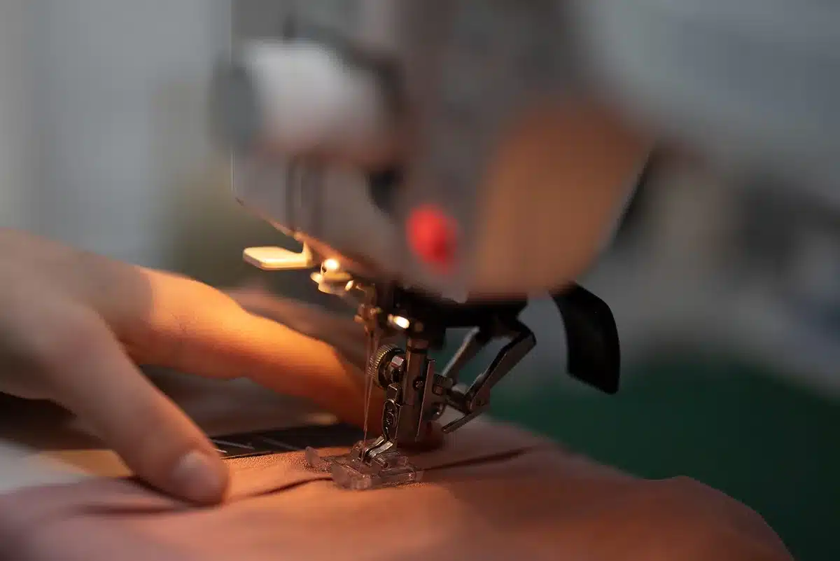 A seamstress working at a sewing machine, close-up of hands and fabric