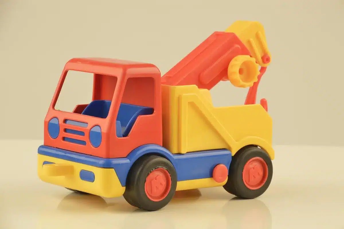 A close-up arrangement of unbranded children's toys and a neutral baby carrier on a simple table, no logos, soft daylight — a holiday-shopping spread evoking gift ideas